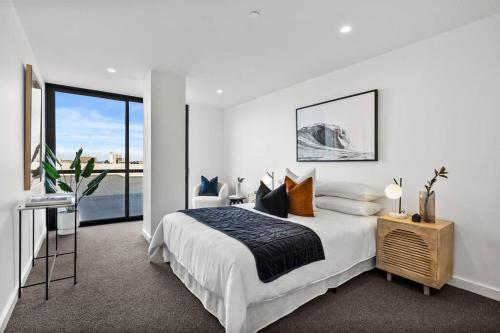 a white bedroom with a bed and a window at Hobart CBD Roof Top Penthouse in Hobart