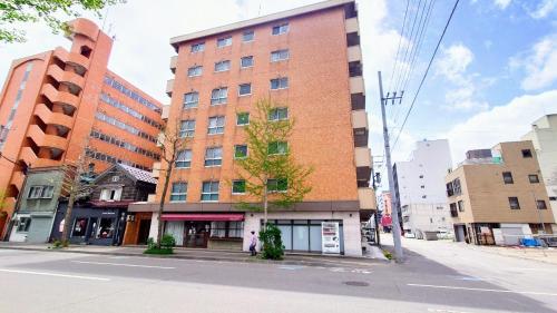 een hoog bakstenen gebouw aan een stadsstraat bij 直前半額プライベート個室トイレバスタブ付民泊札幌市中心部でシンプルな滞在h503#12 in Sapporo