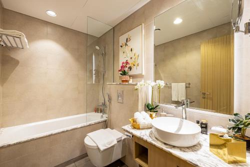 a bathroom with a sink and a tub and a toilet at Stylish 2BR at Paramount Hotel Midtown in Dubai
