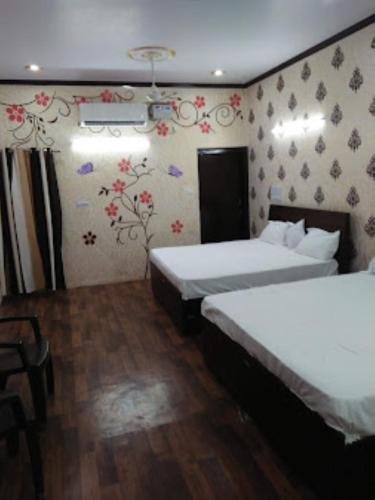 um quarto de hotel com duas camas e papel de parede floral em Kalpana guest house , Bareilly em Bareilly