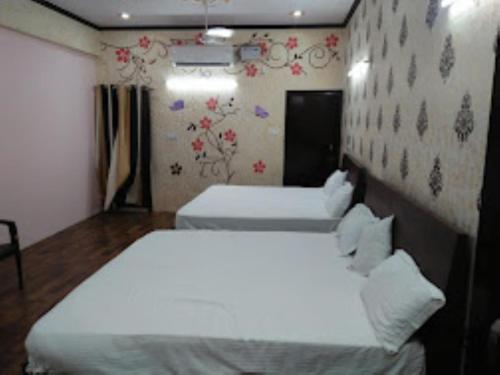 um quarto com duas camas e uma parede com flores em Kalpana guest house , Bareilly em Bareilly