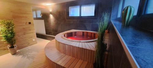 La salle de bains est pourvue d'une baignoire en bois et d'un lavabo rouge. dans l'établissement Alti'Pic Hôtel, à Le Mont-Dore