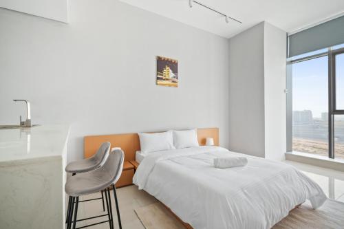 ein weißes Schlafzimmer mit einem Bett und einem Stuhl in der Unterkunft Newly Built Luxury Apt - Pool in Dubai