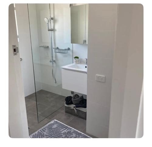 a white bathroom with a sink and a shower at Little Manly Getaway in Sydney