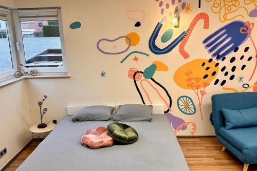 Bett in einem Zimmer mit Wandgemälde in der Unterkunft Le studio Héloïse - BeCosy rentals - 2 ad + 1 enf in Péruwelz