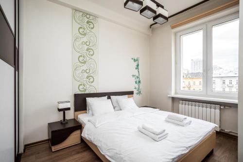 a bedroom with a bed with white sheets and a window at Apartamenty Wawa Centrum by Your Freedom in Warsaw
