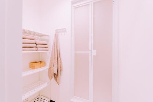 a white bathroom with a shower and towels at Yuzawa Onsen Lodge 1min to LIFT A House in Seki