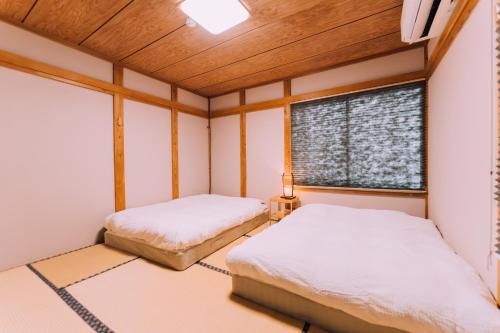 two beds in a room with a window at Yuzawa Onsen Lodge 1min to LIFT A House in Seki
