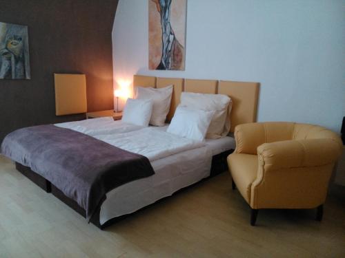 a bedroom with a large bed and a chair at Apartment Sova in Ostrava