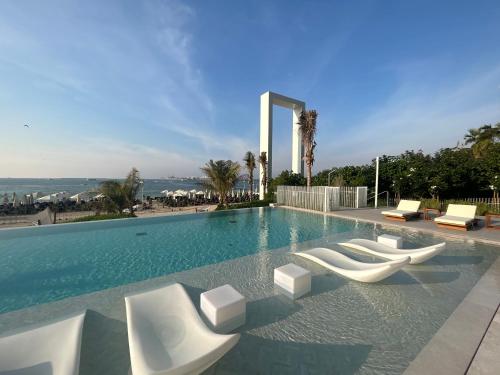 a swimming pool with white lounge chairs and the ocean at La Vie, JBR private beach, private parking and pool in Dubai