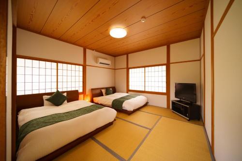 a room with two beds and a flat screen tv at Yufuin Kurokiya - Vacation STAY 85694 in Yufuin