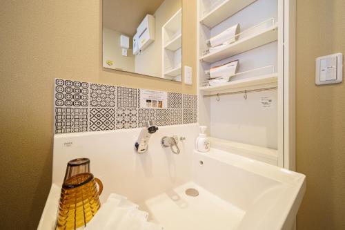Baño blanco con lavabo y espejo en Chachamaru no Oyado - Vacation STAY 85728, en Yufu