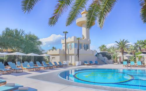 a resort with a pool and chairs and a building at Minareto in Siracusa