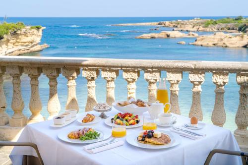 una mesa con platos de comida en un balcón con vistas al océano en Minareto en Siracusa