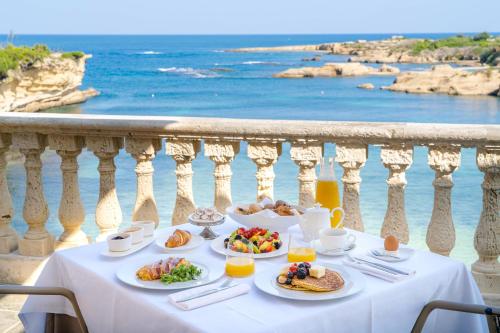 a table with plates of food on a balcony with the ocean at Minareto in Siracusa
