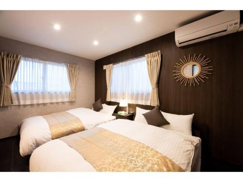 BEPPU NO YU TSUKI - Vacation STAY 87965 في بيبو: غرفة نوم بسريرين ومرآة على الحائط