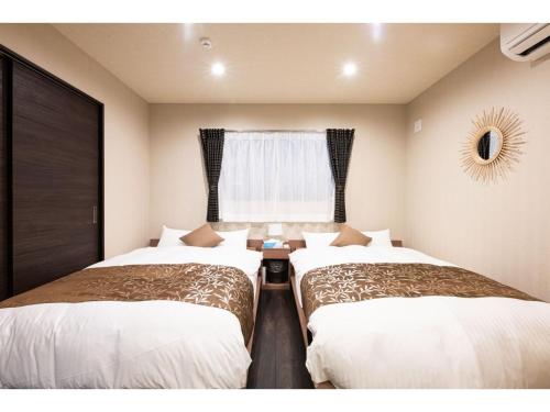 two beds in a room with a window at BEPPU NO YU SARA - Vacation STAY 87960 in Beppu