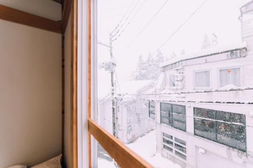 a window with a view of a building at Yuzawa Onsen Lodge 1min to LIFT House in Seki