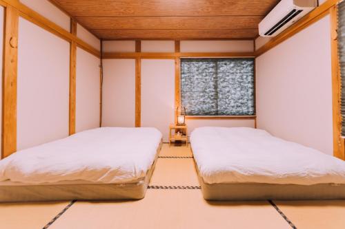two beds in a room with a window at Yuzawa Onsen Lodge 1min to LIFT House in Seki