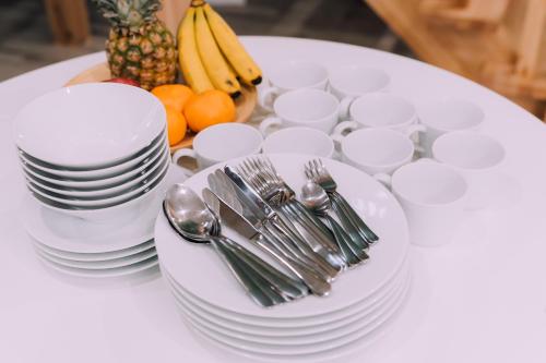 a table with white plates and forks and spoons and fruit at Yuzawa Onsen Lodge 1min to LIFT House in Seki