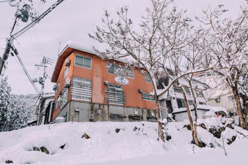 a building is covered in snow in front at Yuzawa Onsen Lodge 1min to LIFT House in Seki