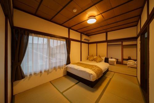 a bedroom with a bed and a window at Yufuin Ekimae Yado Kachofugetsu - Vacation STAY 88189v in Yufuin