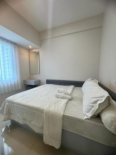 ein Schlafzimmer mit einem großen Bett mit weißer Bettwäsche und Kissen in der Unterkunft Tanglin Orchard Apartment by Kondoku in Lontar
