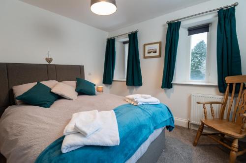 1 dormitorio con 1 cama con cortinas azules y silla en Crabtree Barn en Halifax
