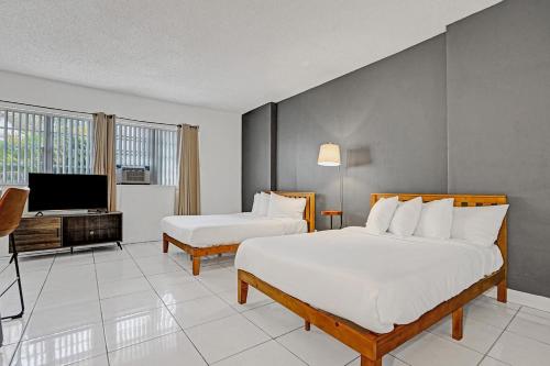 a hotel room with two beds and a television at Walk to the Beach Seasonal Vacation Home Pool in Hallandale Beach