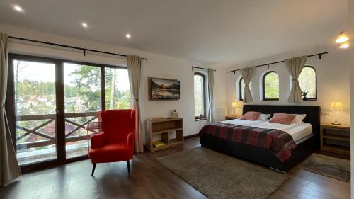 a bedroom with a bed and a red chair at Alfinio Villa in Sinaia