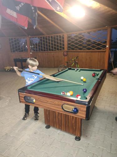 a young boy playing pool on a pool table at Chatka in Stegienka