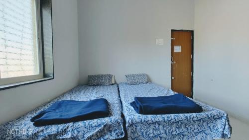 um quarto com 2 camas com lençóis azuis e uma janela em Aadishkti bhakt nivas em Tuljapur