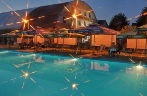 une grande piscine avec des parasols et un bâtiment dans l'établissement sporski centar okanik, à Mataruška Banja