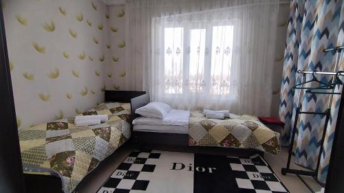 a bedroom with two twin beds and a window at Datka Guesthouse in Karakol