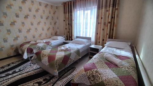 a bedroom with two beds and a window at Datka Guesthouse in Karakol