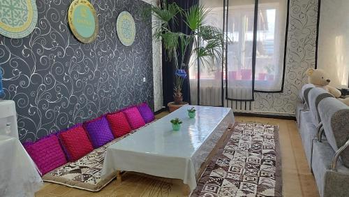 a living room with a white table and pink couch at Datka Guesthouse in Karakol