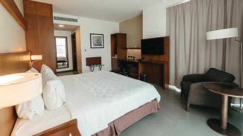 a hotel room with a large bed and a chair at Holiday Inn Guayaquil Airport by IHG in Guayaquil