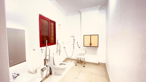 a white bathroom with a toilet and a shower at Al Quba Al Thahbia Hotel Suites 2 in Riyadh