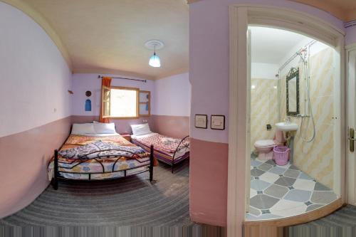 um quarto com 2 camas e uma cabina de duche ao nível do chão em Hotel De La Vallée em Aït Baha