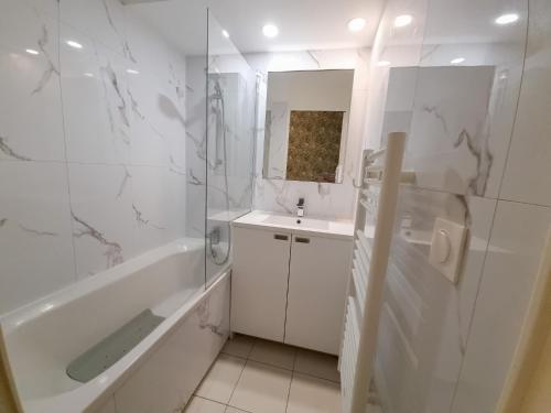 La salle de bains blanche est pourvue d'une baignoire et d'un lavabo. dans l'établissement Appartement 3P traversant vue mer et forêt - Les clés de l´Estérel, à Théoule-sur-Mer