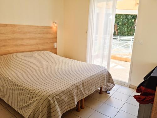 Schlafzimmer mit einem Bett mit gestreifter Tagesdecke in der Unterkunft Appartement 3P traversant vue mer et forêt - Les clés de l´Estérel in Théoule-sur-Mer