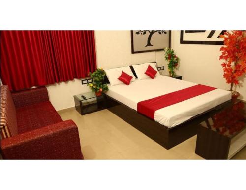 a bedroom with a bed and a red chair at Hotel Bhagwati International, Abu Road, Rajasthan in Ābu Road
