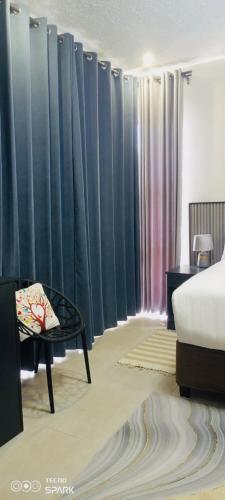 um quarto com uma cama, uma mesa e cortinas em Sewelo inn guesthouse em Maun