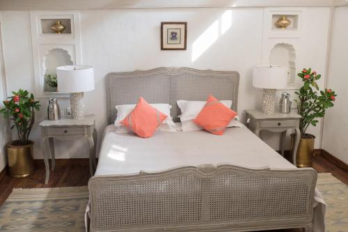a bedroom with a bed with orange and white pillows at Ahilya Fort in Maheshwar