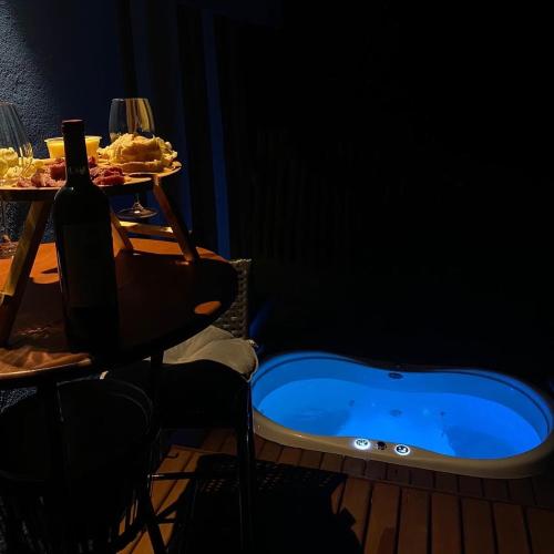 a bath tub with a table and a bottle of wine at Estalagem Meraki - Cunha SP in Cunha