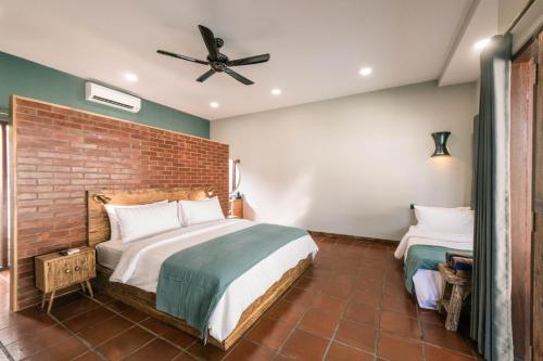 a bedroom with a bed and a brick wall at Belukar Villas in Gili Trawangan