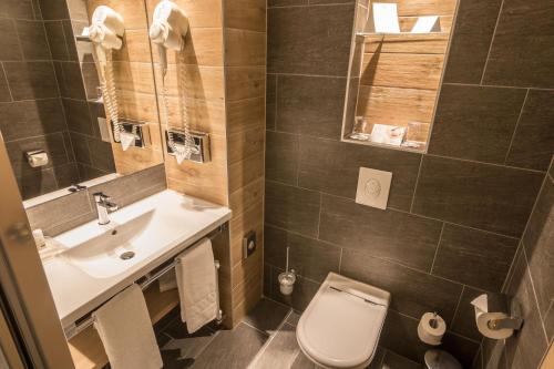 a bathroom with a sink and a toilet and a mirror at Holiday Inn Budapest-Budaörs, an IHG Hotel in Budaörs