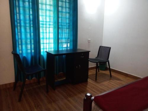 a desk and two chairs in a room with blue curtains at River View Guest Rooms in Vythiri