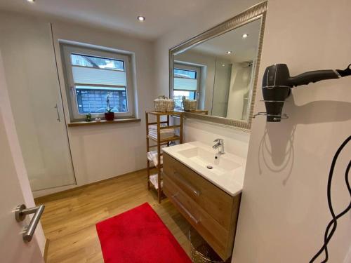 uma casa de banho com um lavatório e um espelho grande em Herzzeit Apartments em Flachau