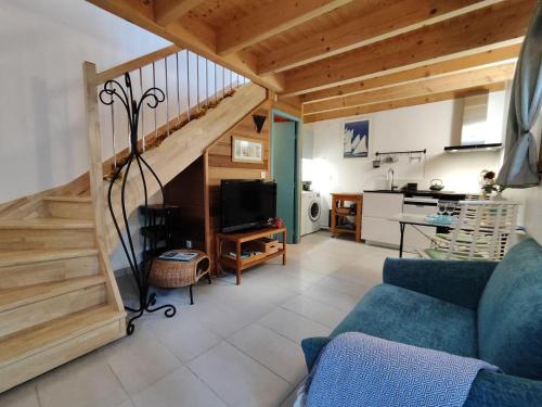 uma sala de estar com um sofá azul e uma escada em La Grange aux hirondelles em Laroque-des-Albères
